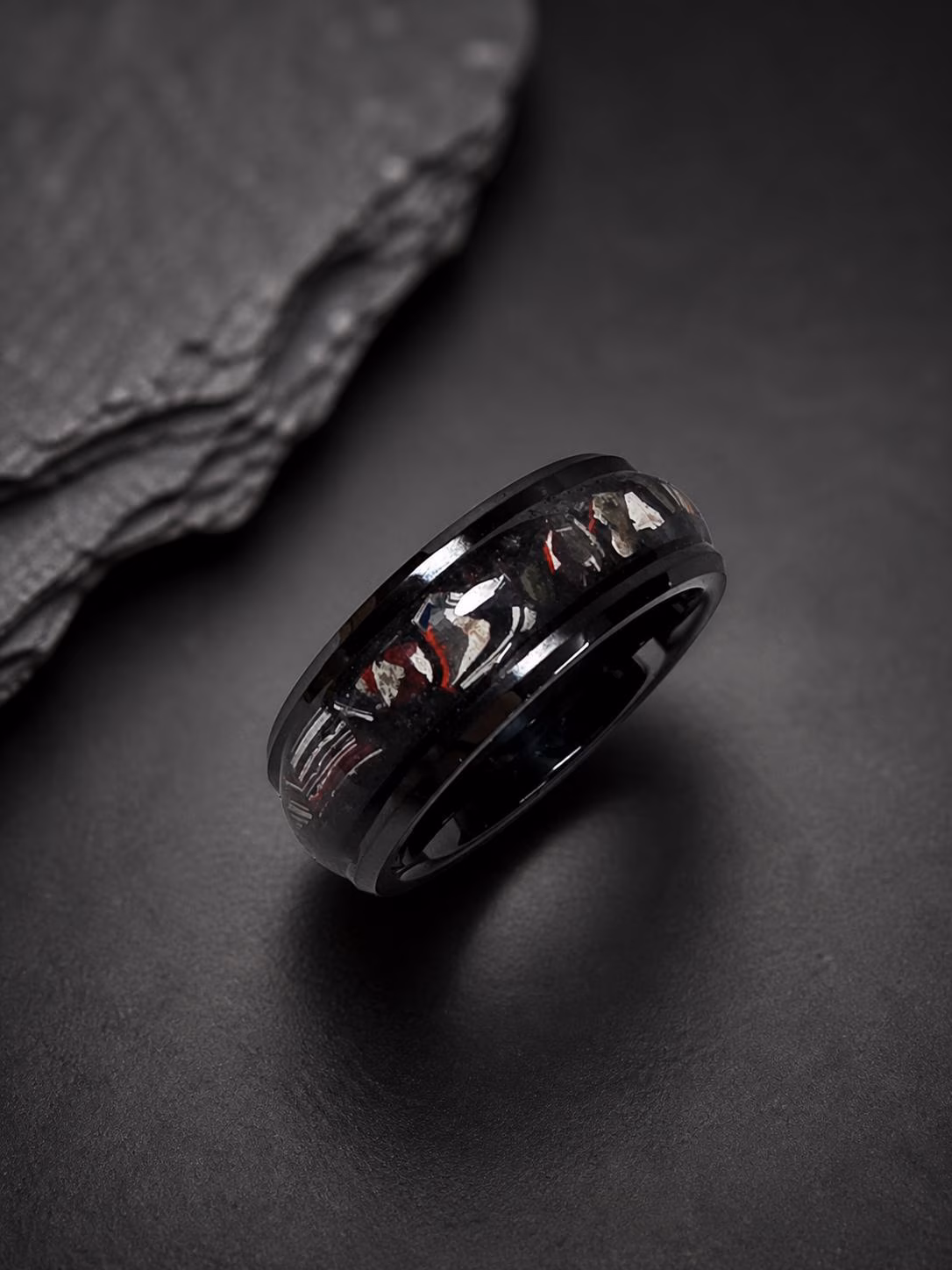 Genuine Fordite black ceramic ring showing unique red white blue and black paint layers